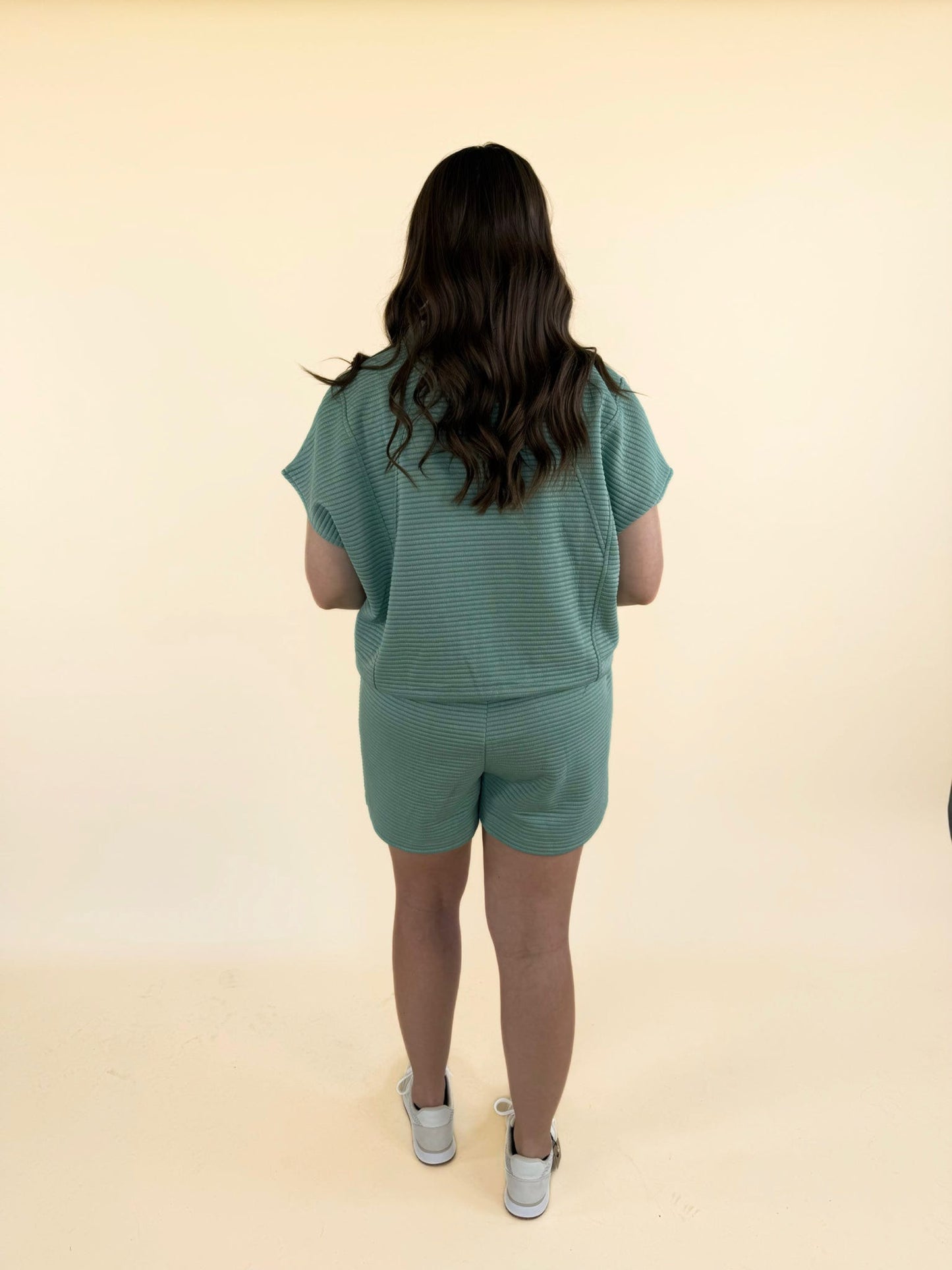 Back view of women’s green quilted two-piece set with relaxed fit top and elastic waist shorts casual loungewear