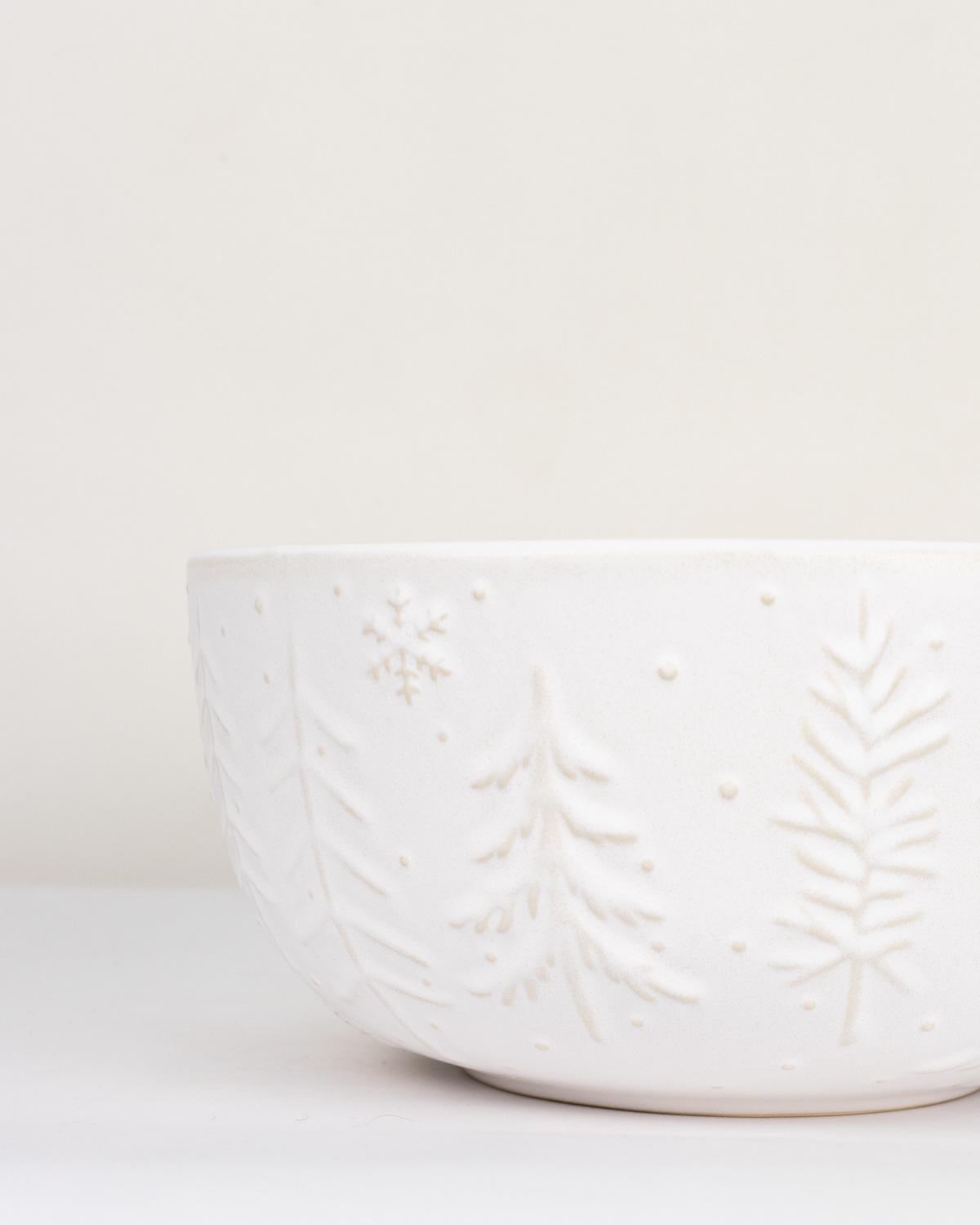 White ceramic bowl with leaf pattern on a white background