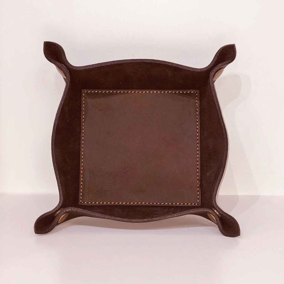 Brown leather tray with nailhead trim on a white background