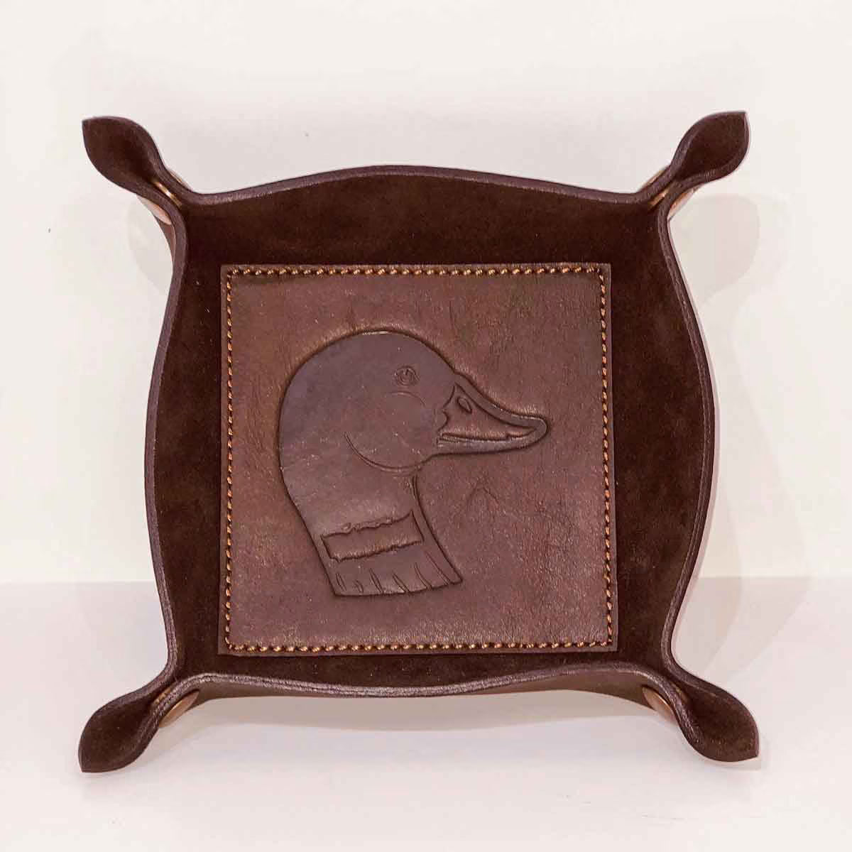 Brown leather tray with embossed duck design on a white background
