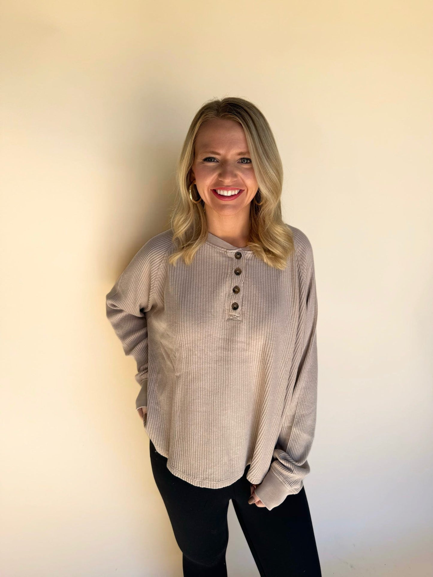 Woman wearing a dark taupe long-sleeve shirt with buttons against a plain background