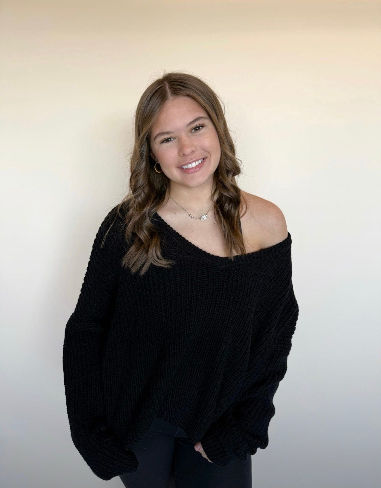 Woman wearing a black sweater against a plain background