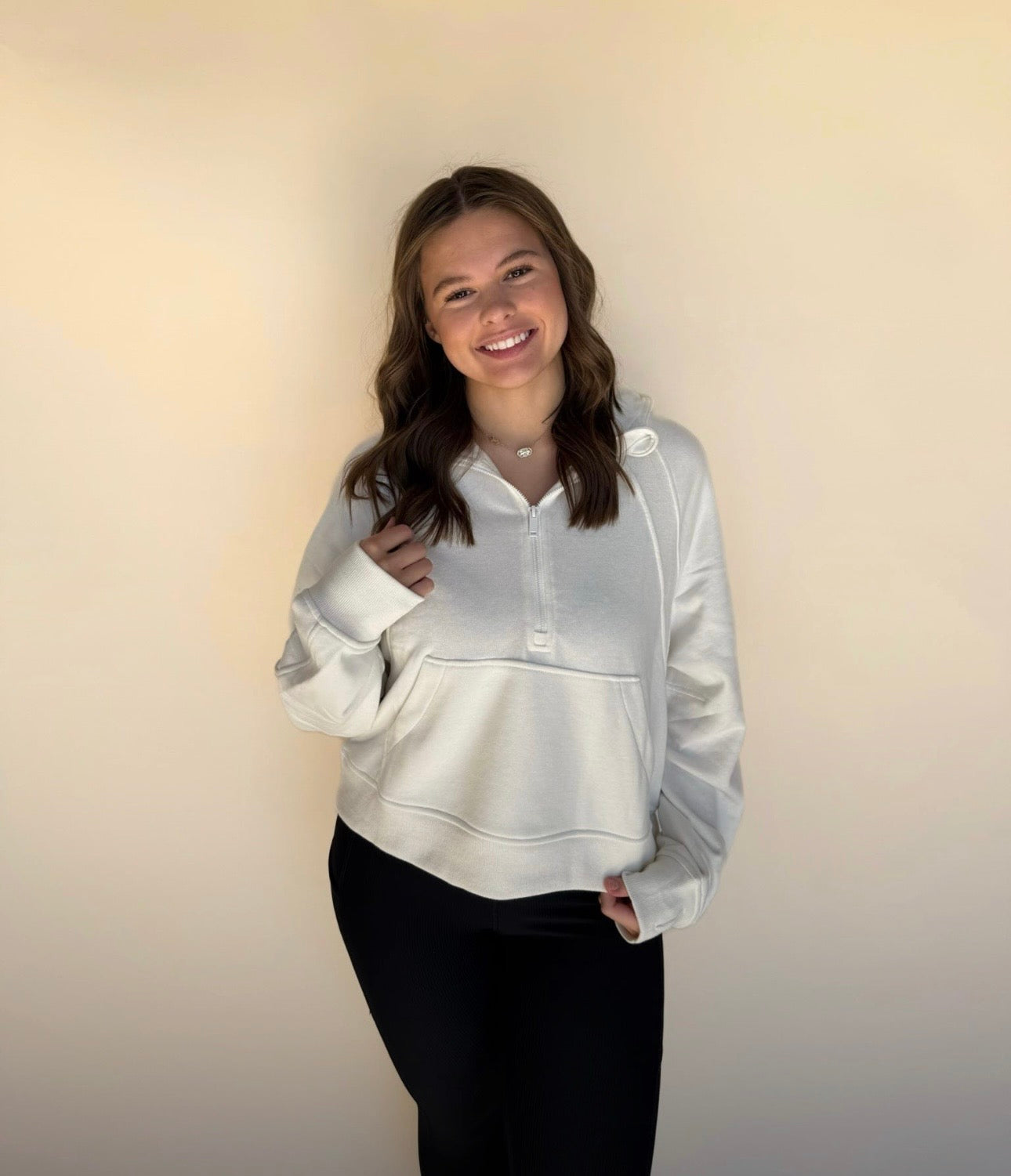 Person wearing an off white hoodie against a plain background