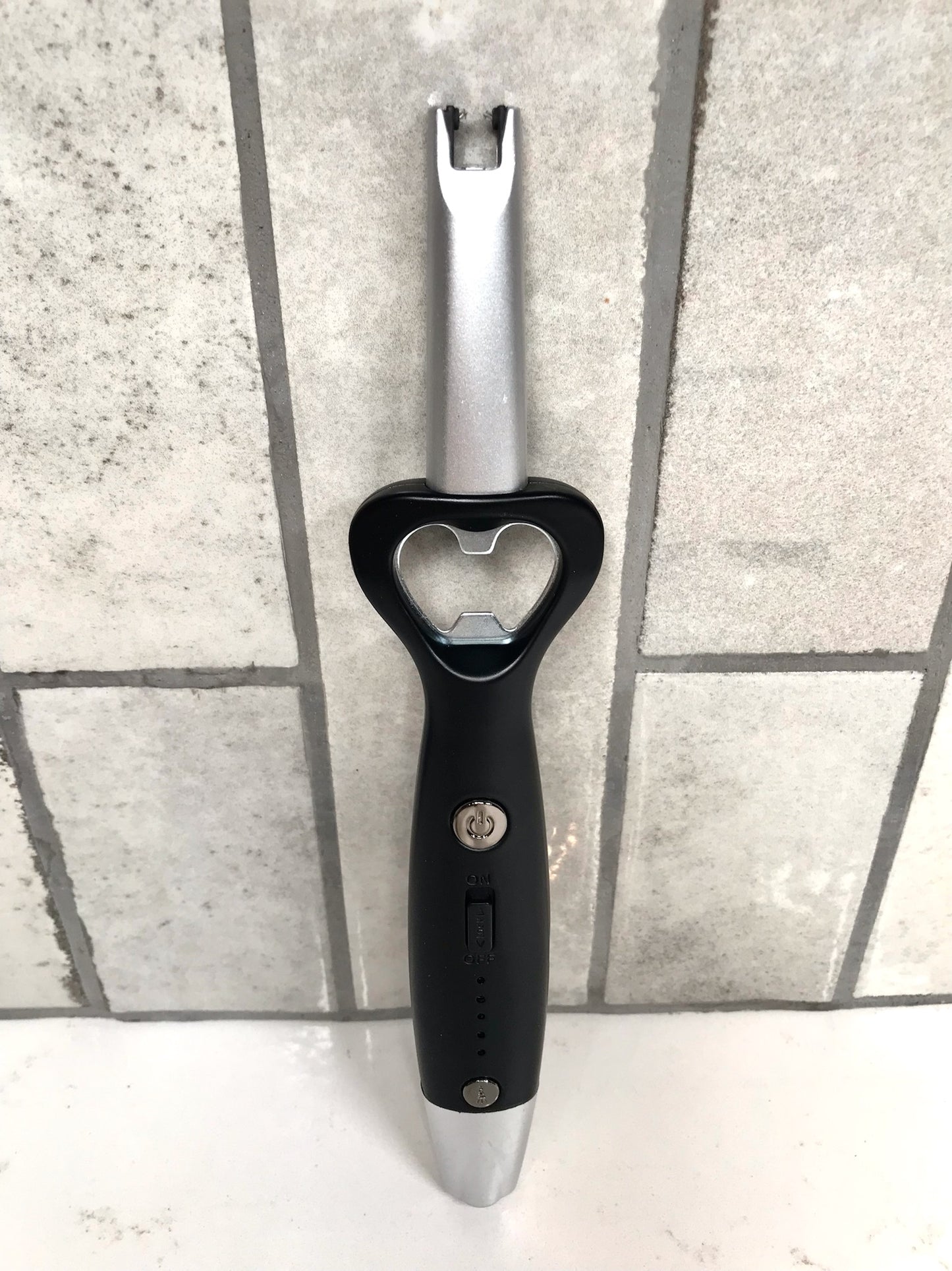 Black and silver bottle opener on a tiled floor