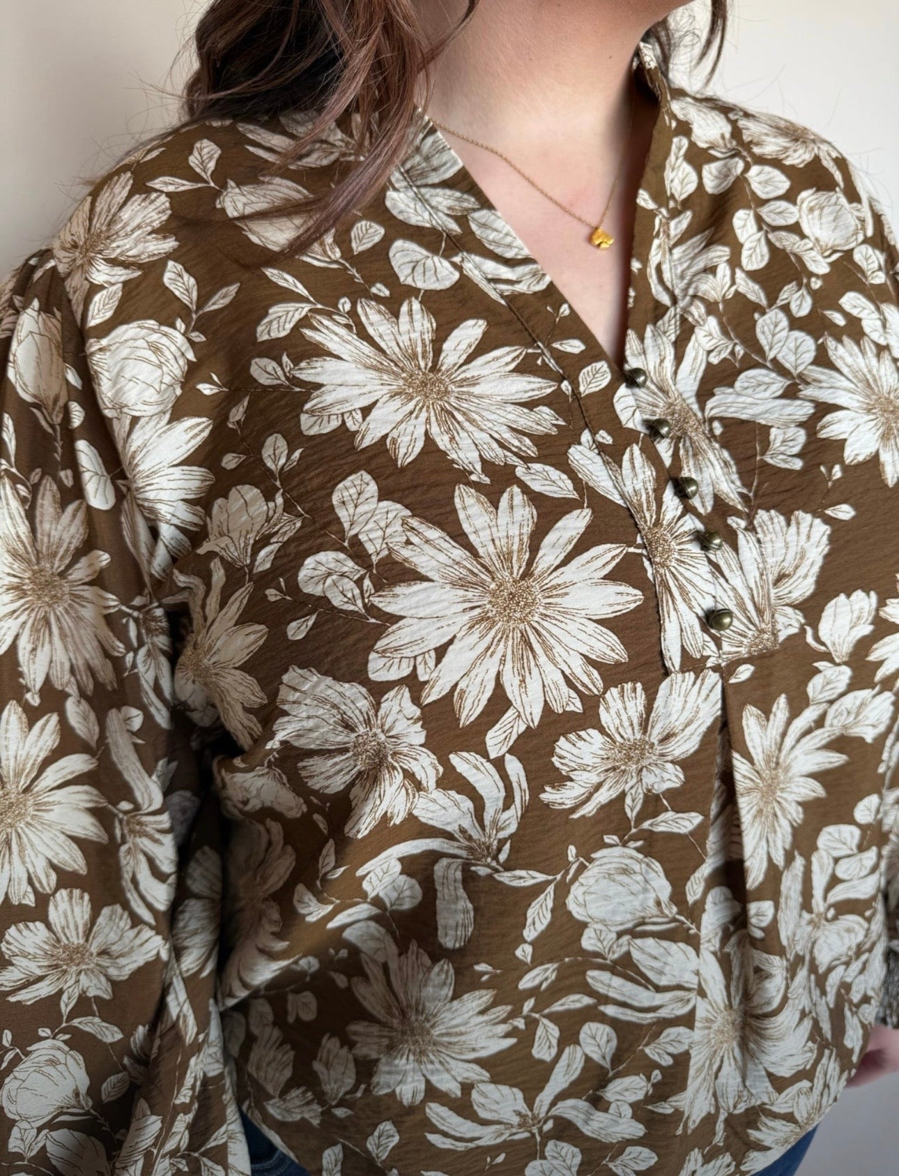 Close-up of brown floral blouse showing ivory oversized flowers, split neckline, and small button detail.