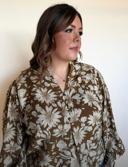 Woman wearing a brown long-sleeve floral blouse with ivory oversized flower print, split neckline, and relaxed fit.