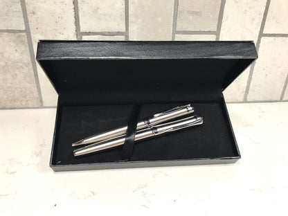 Two silver pens in a black box on a tiled floor