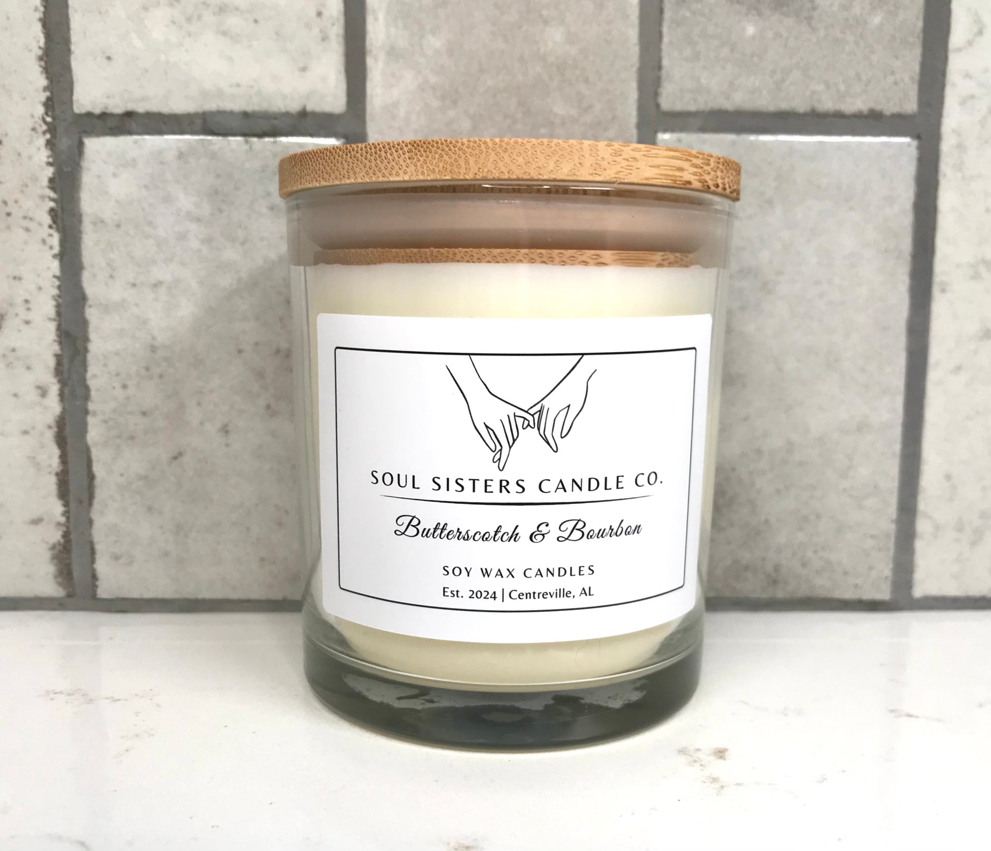 Scented candle with a wooden lid on a tiled surface