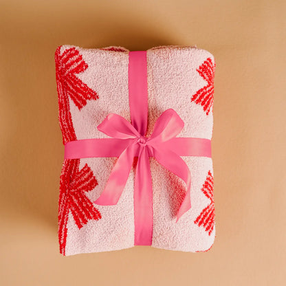 Folded towel with red patterns and a pink ribbon on a beige background