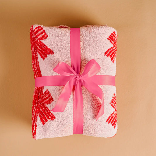 Folded towel with red patterns and a pink ribbon on a beige background