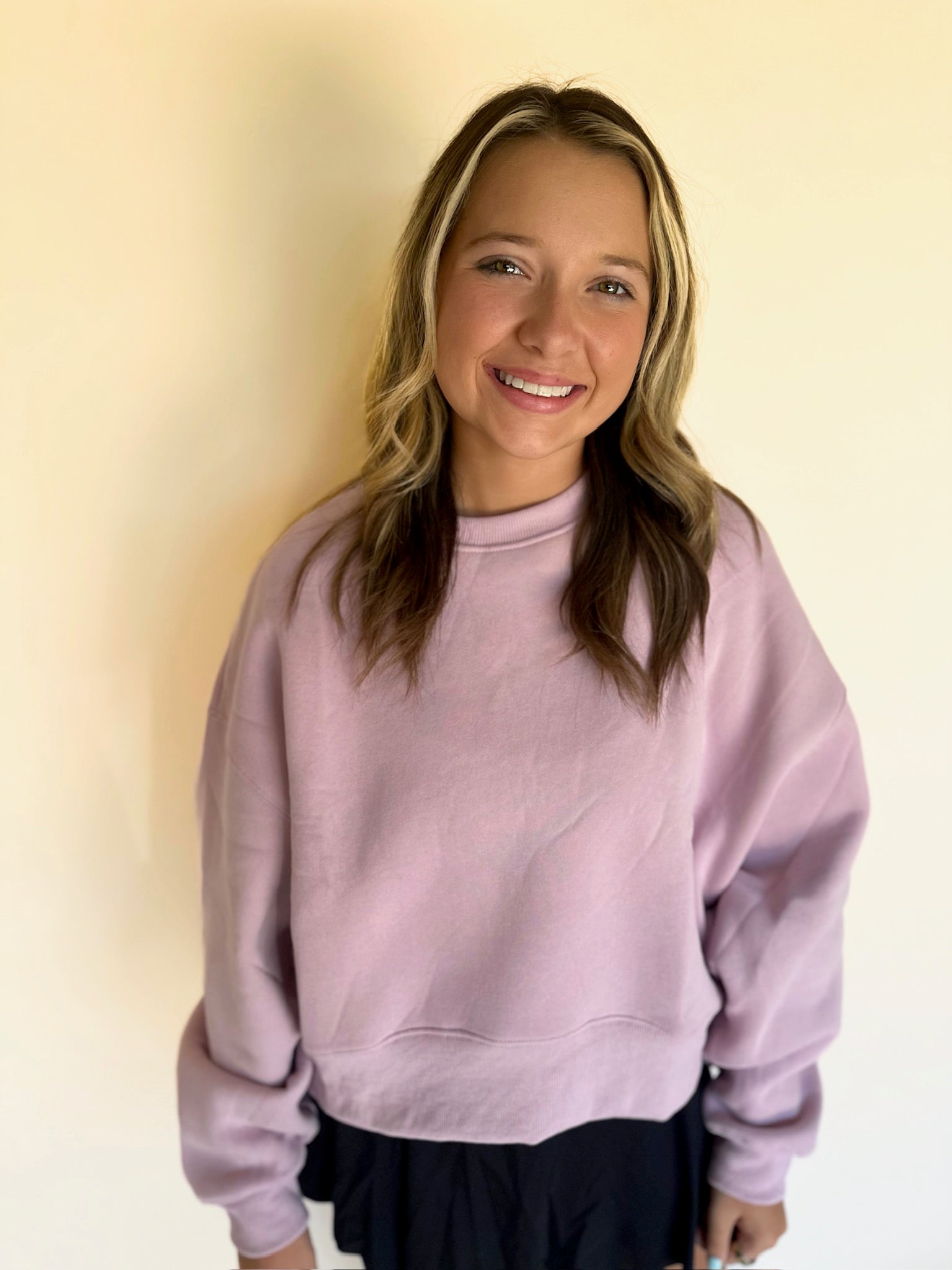 Woman wearing a light purple sweatshirt against a beige background