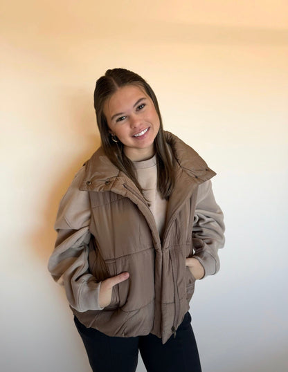 Person wearing a beige puffer vest against a plain background