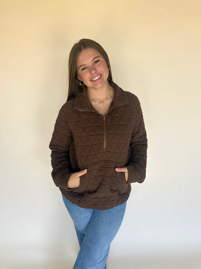 Woman wearing a brown quilted jacket against a plain background