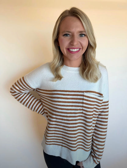 Woman wearing a white sweater with brown horizontal stripes against a plain background