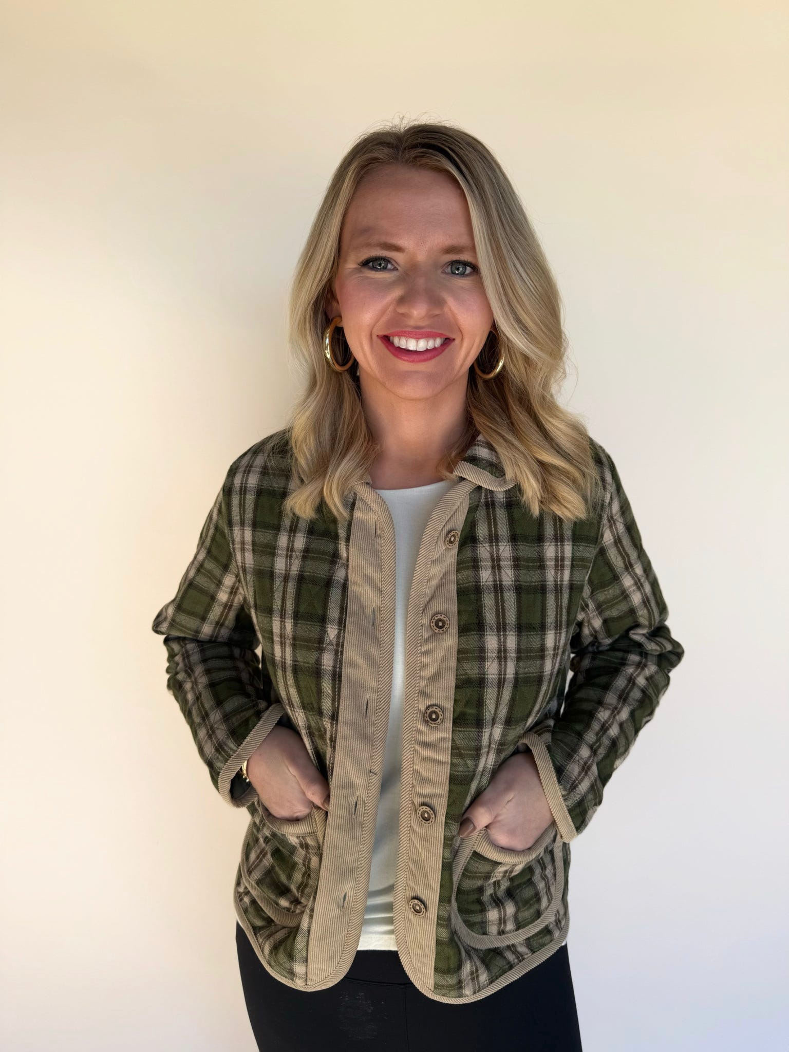 Front view of woman wearing a green and tan plaid jacket with corduroy button placket and pockets, styled over a white top.