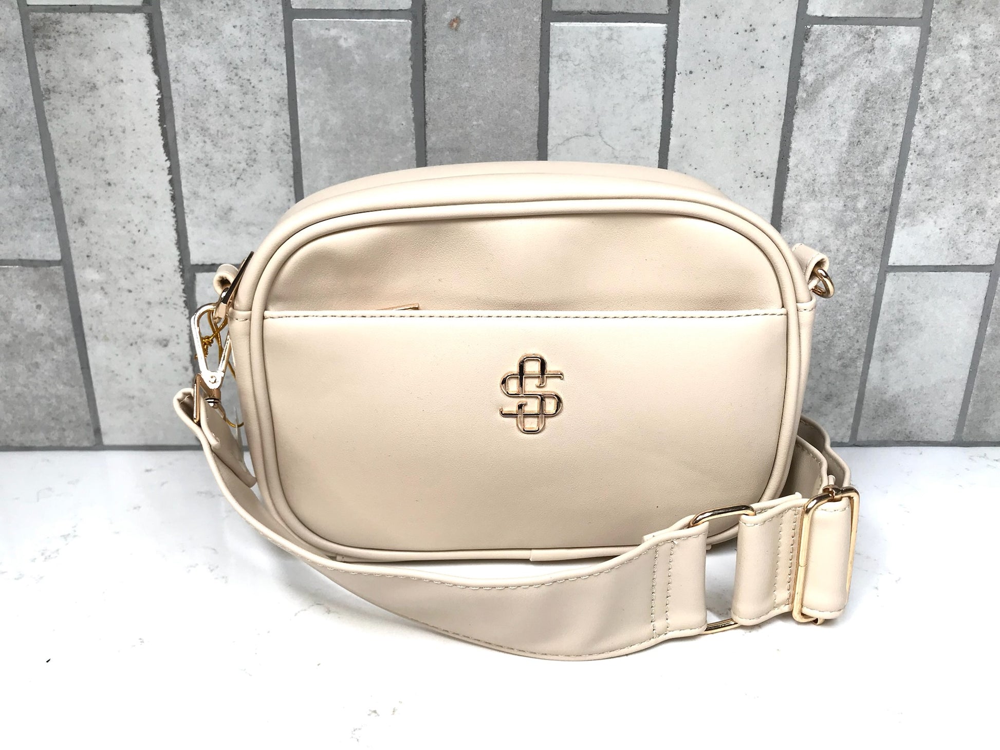 Beige handbag with a brand logo on a light gray background
