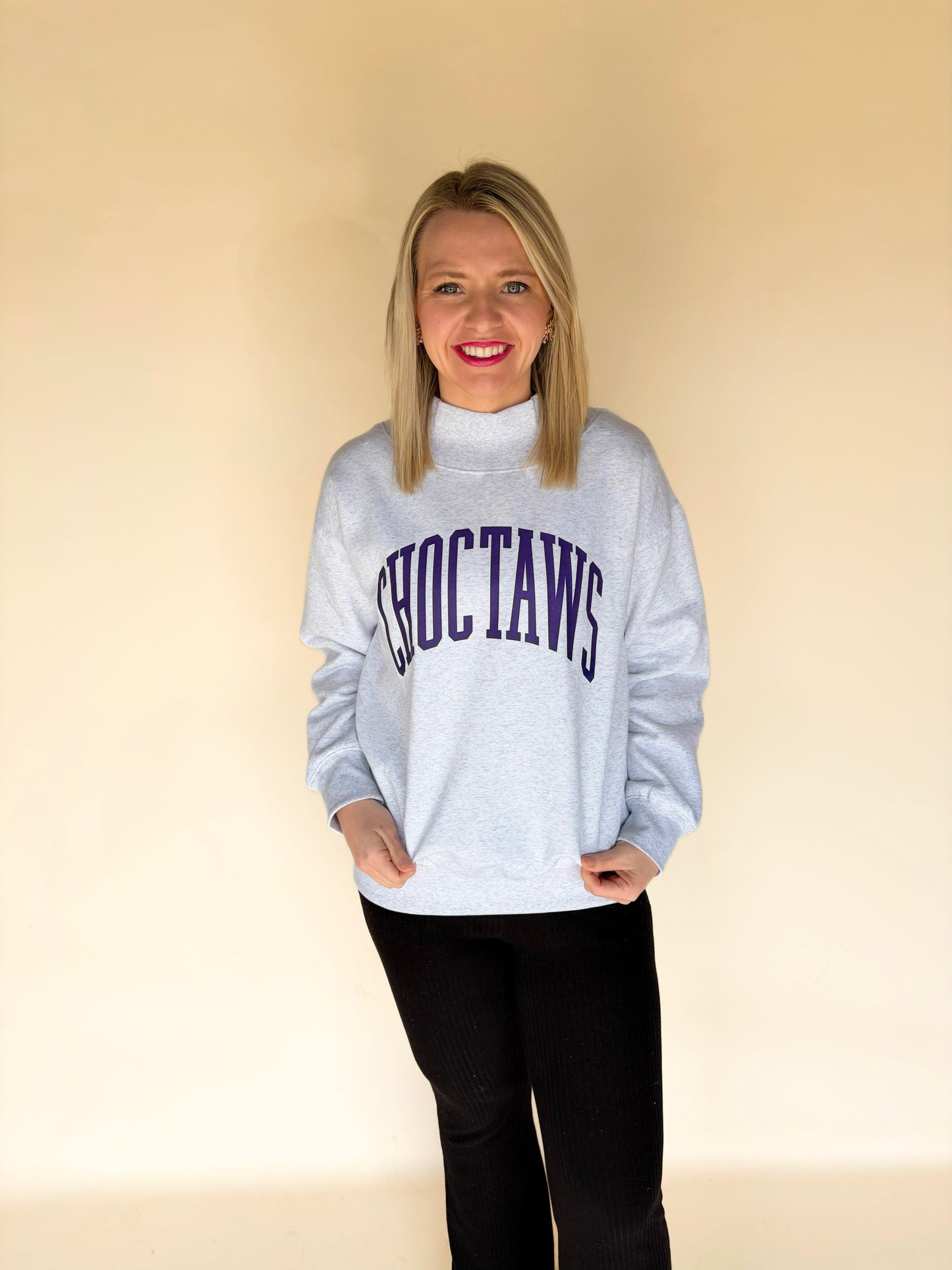 Full body view of woman modeling light gray Choctaws mock neck sweatshirt with purple varsity lettering, oversized boutique pullover sweatshirt
