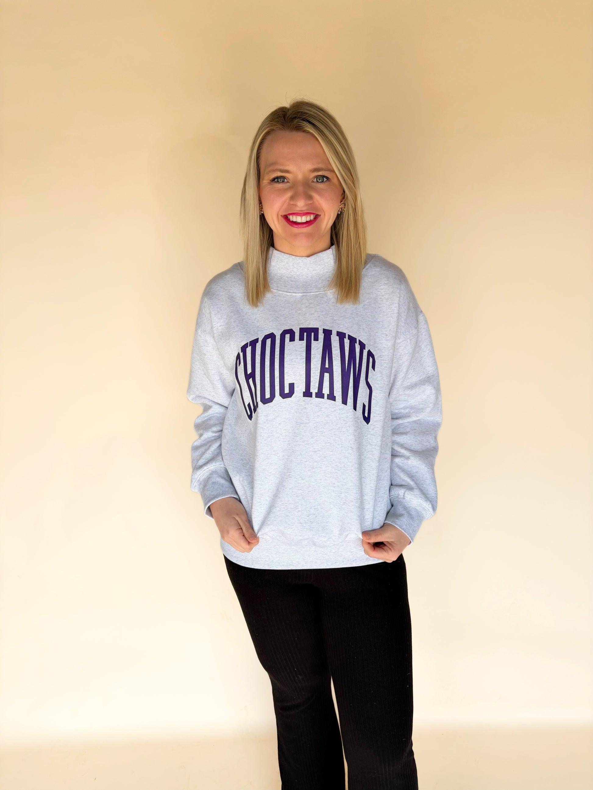 Full body view of woman modeling light gray Choctaws mock neck sweatshirt with purple varsity lettering, oversized boutique pullover sweatshirt
