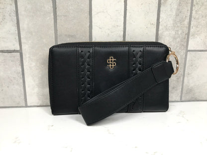 Black handbag with a strap on a white surface with a tiled background