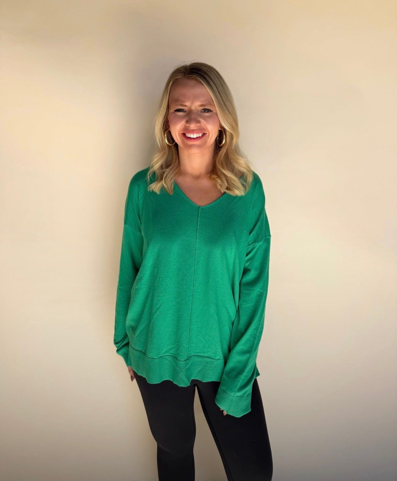 Woman wearing a green long-sleeve top against a plain background