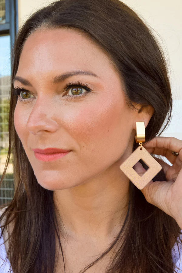 Woman wearing a beige earring with a gold hook