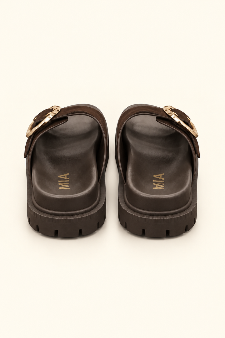 Rear view of dark brown platform slide sandals showing molded footbeds, gold logo lettering, and lug soles.