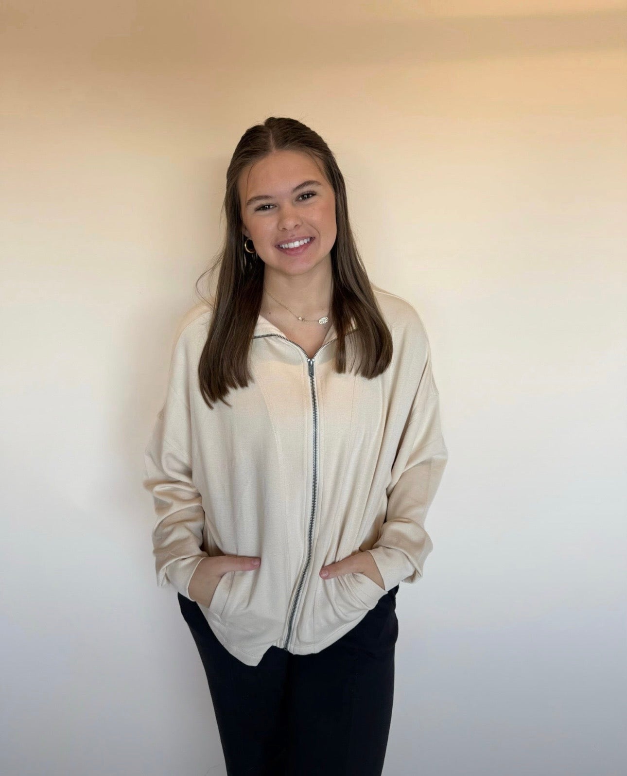 Person wearing a beige zip-up sweater against a plain background