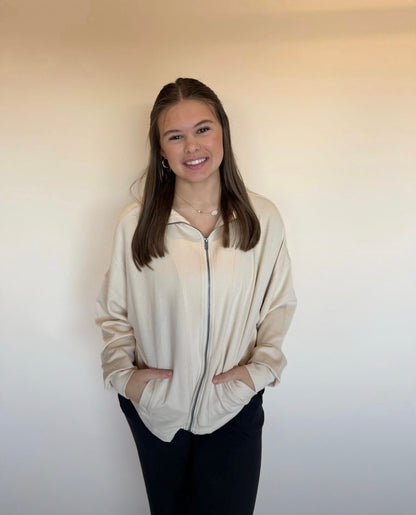 Person wearing a beige zip-up sweater against a plain background