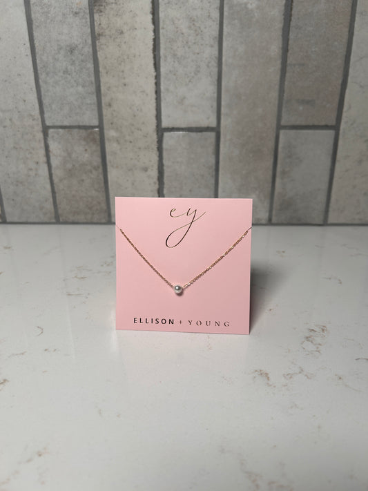 Dainty single pearl necklace on a gold chain by Ellison + Young, minimalist everyday jewelry displayed on pink card