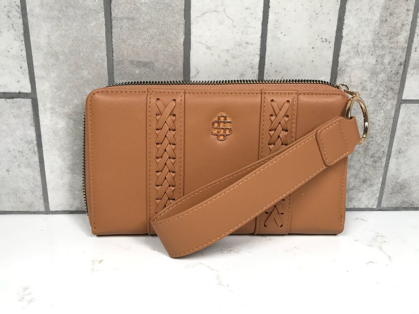Brown leather handbag with a strap on a gray and white background