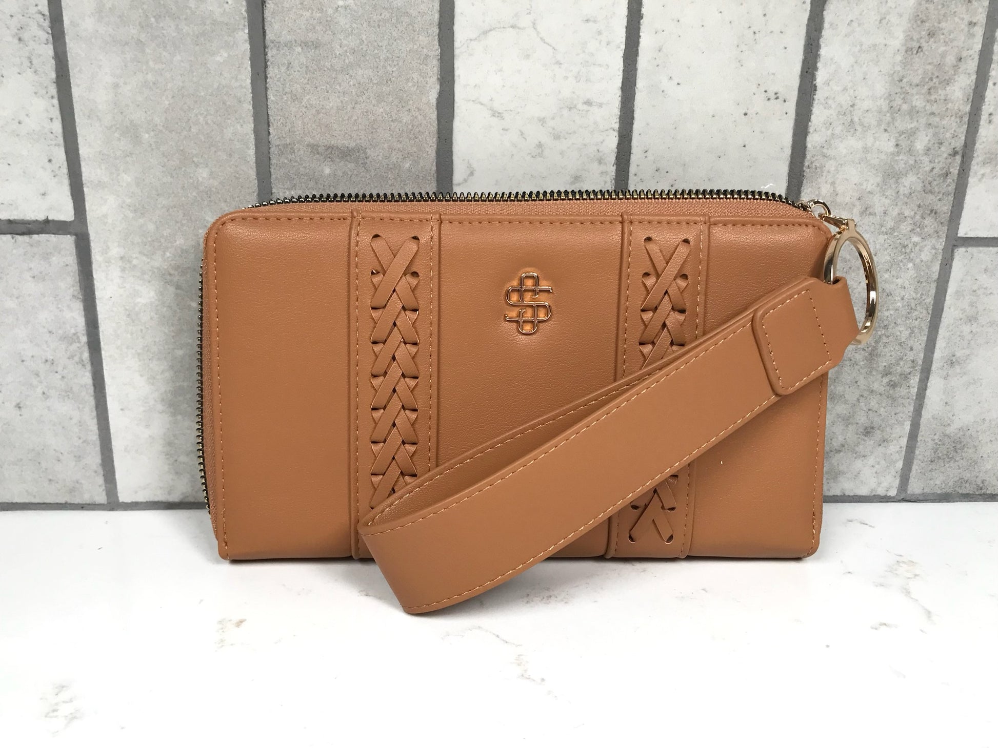 Brown leather handbag with a strap on a gray and white background