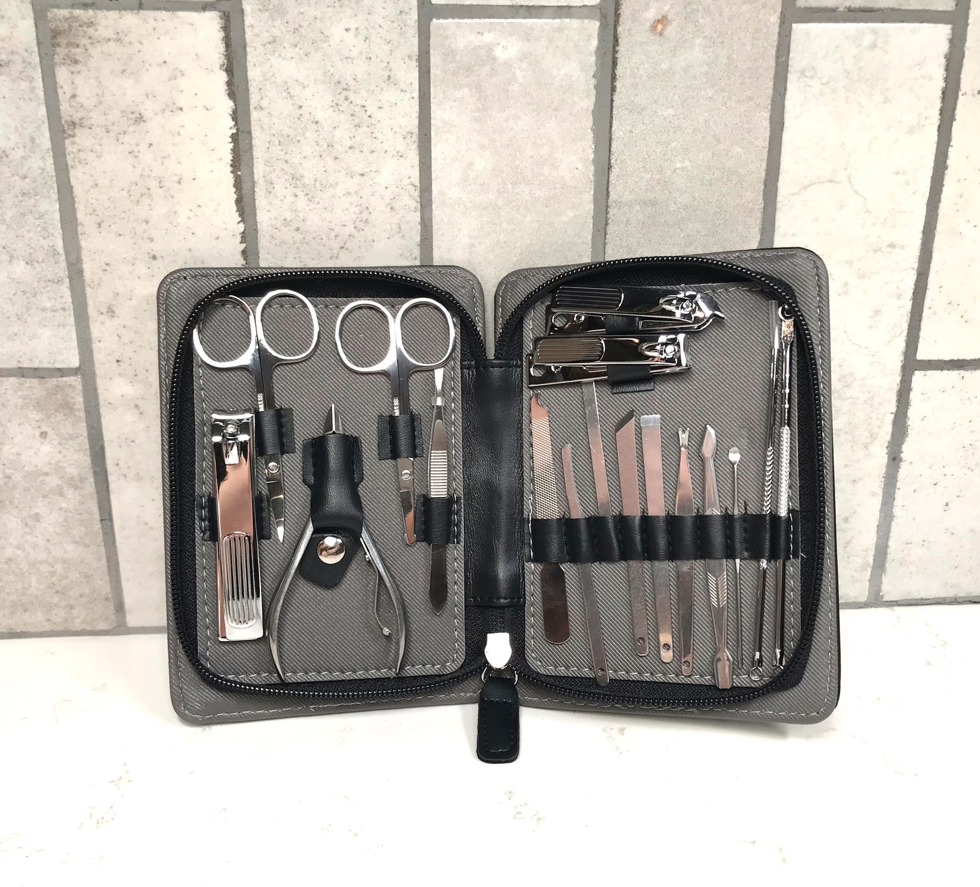 Manicure and pedicure set with tools in a black case on a tiled floor.