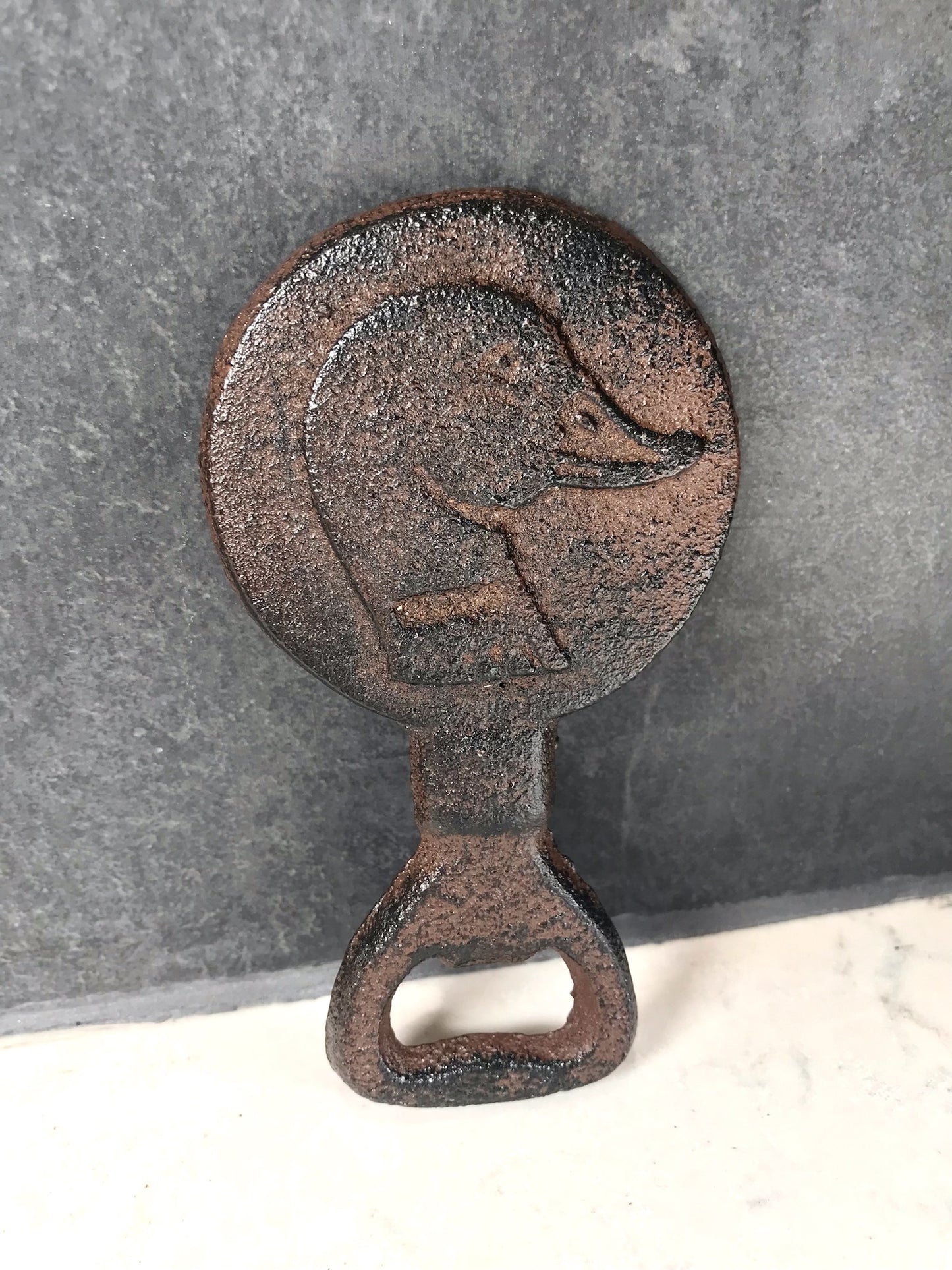 Rustic metal bottle opener with duck design on a gray background