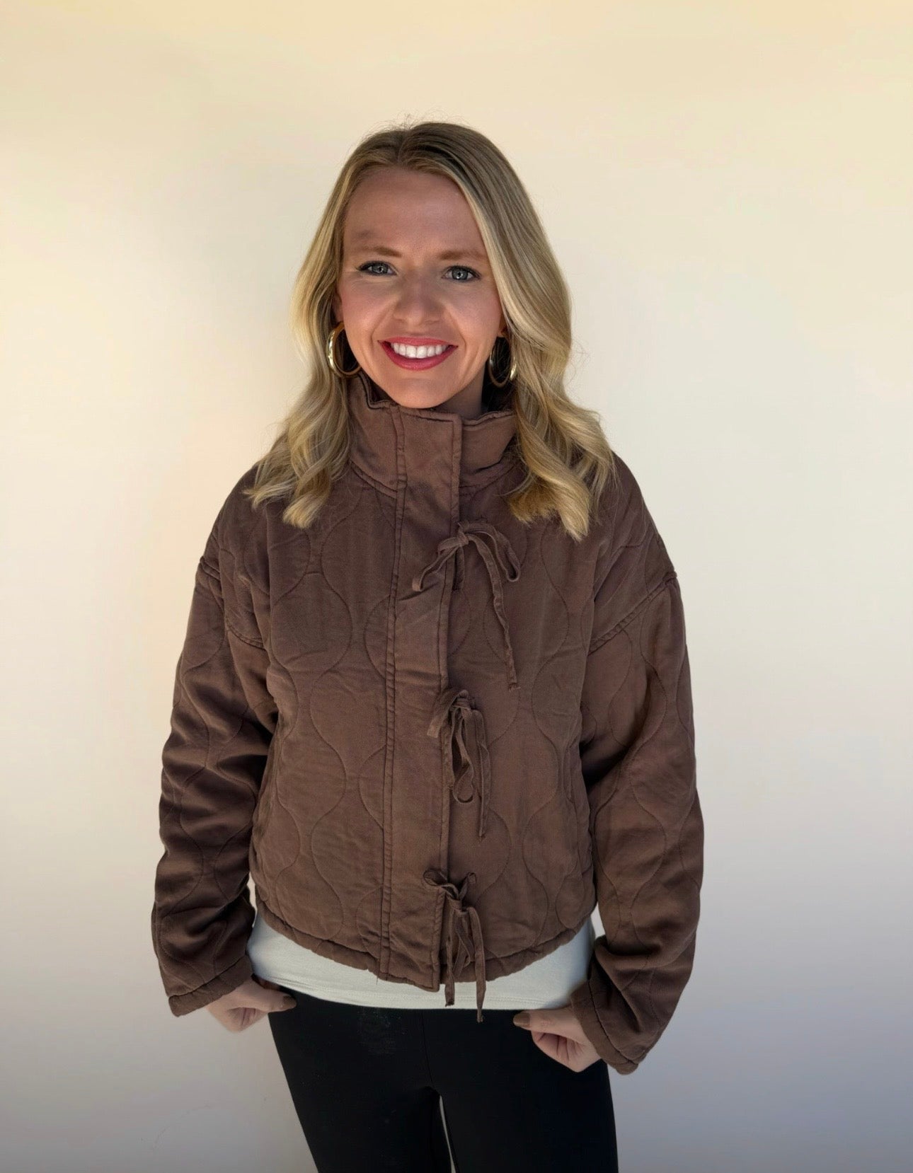 Woman wearing a brown jacket against a plain background
