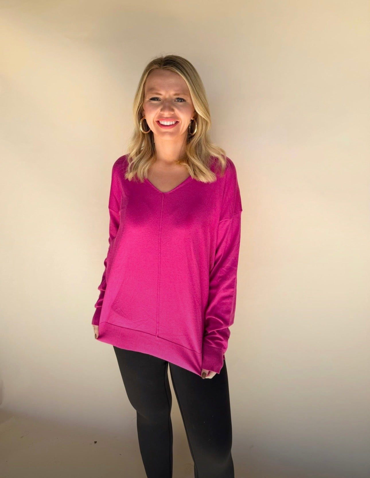 Woman wearing a bright pink sweatshirt against a plain background