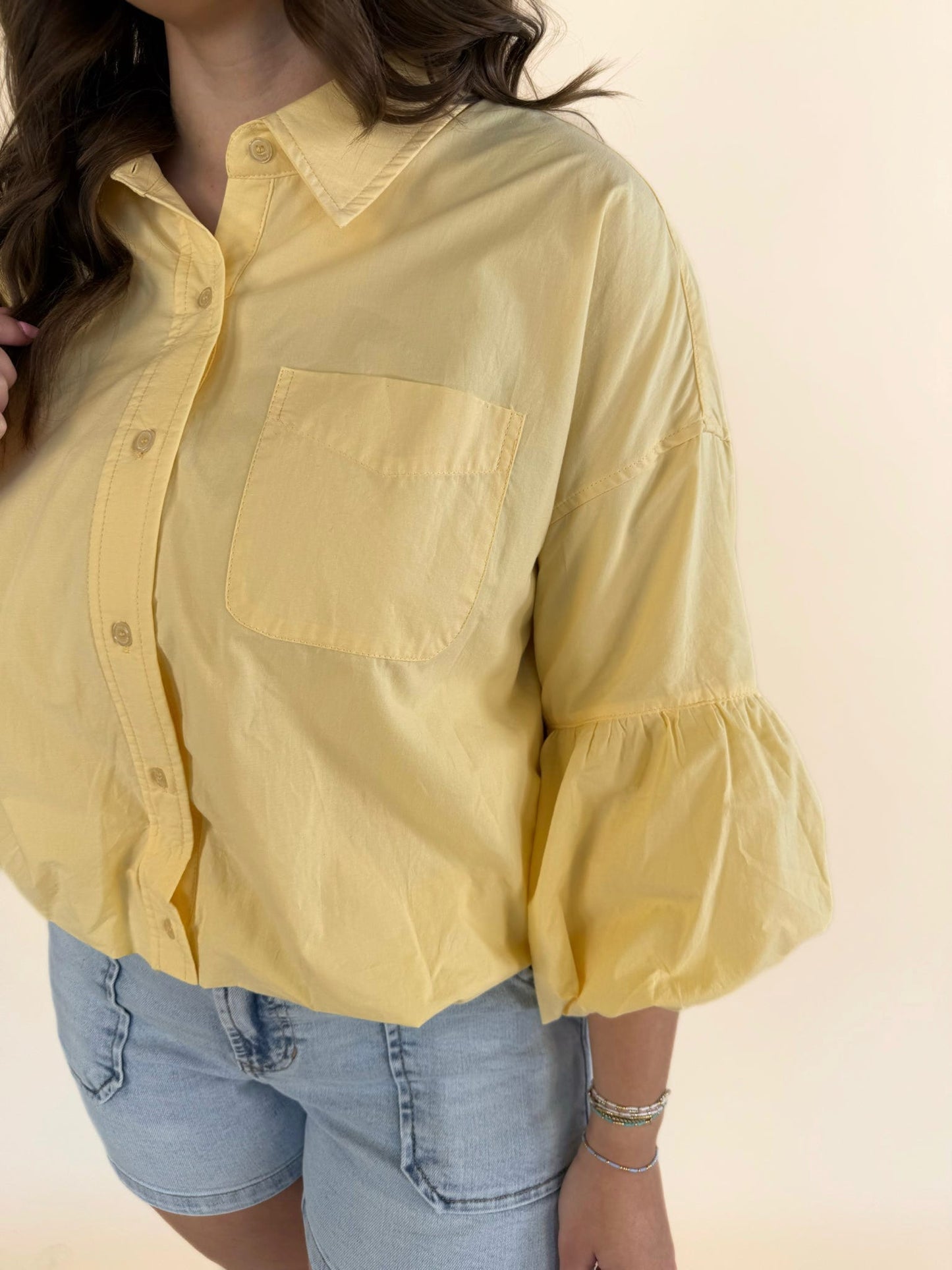 Detail of balloon sleeve cuff and soft cotton fabric on banana cream yellow button-down blouse
