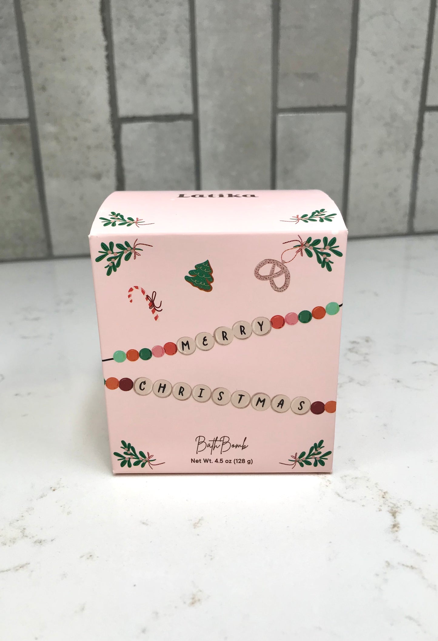 Pink Christmas-themed box on a white surface with a tiled wall background