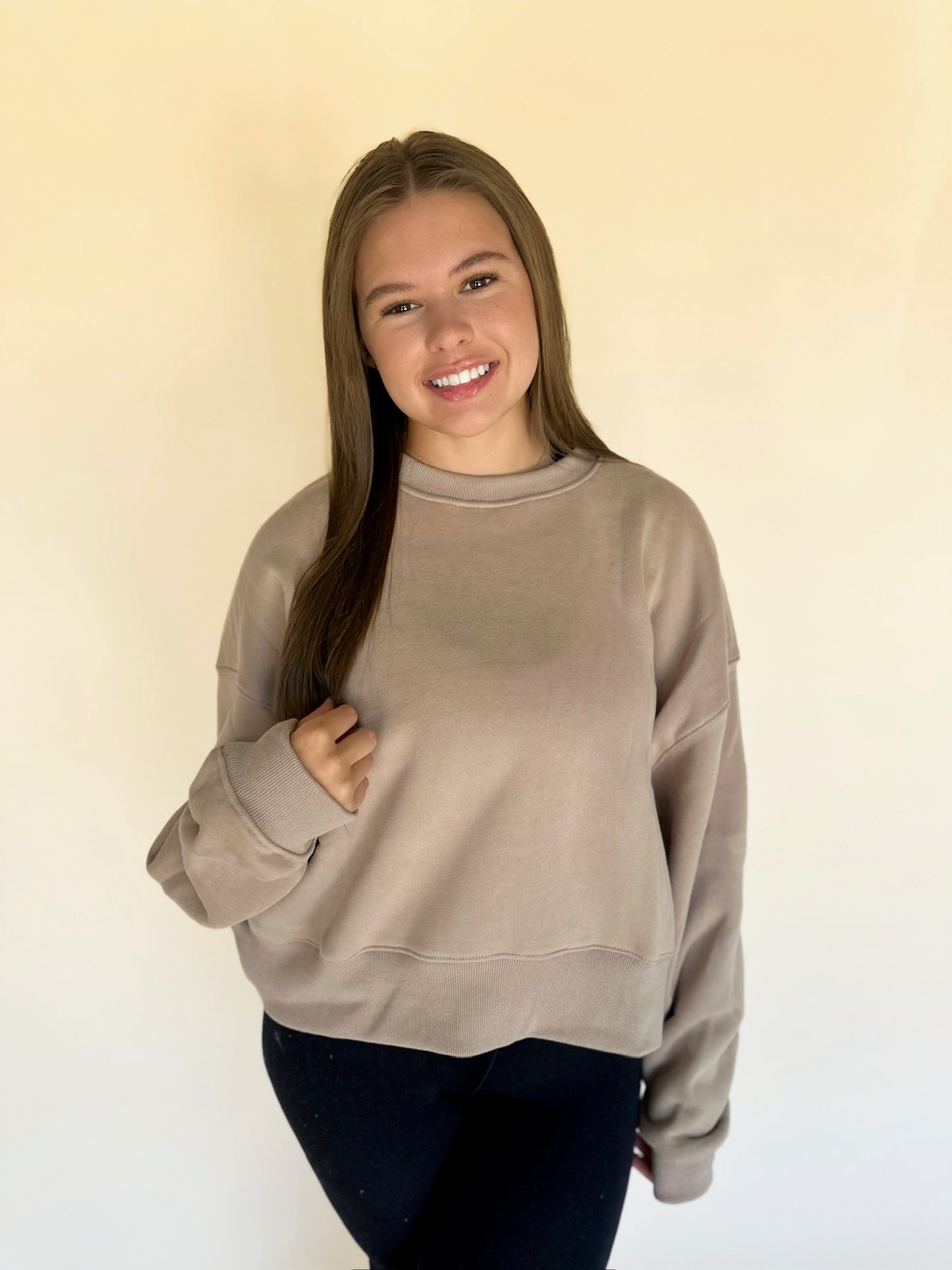 Woman wearing a beige sweatshirt against a plain background