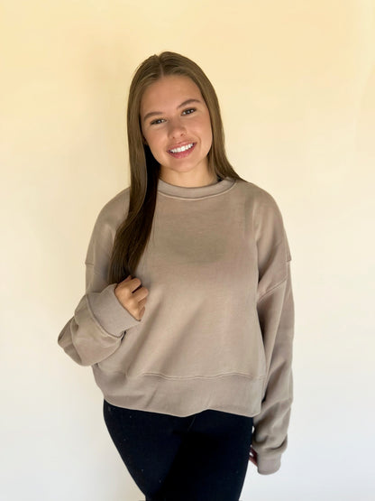 Woman wearing a beige sweatshirt against a plain background