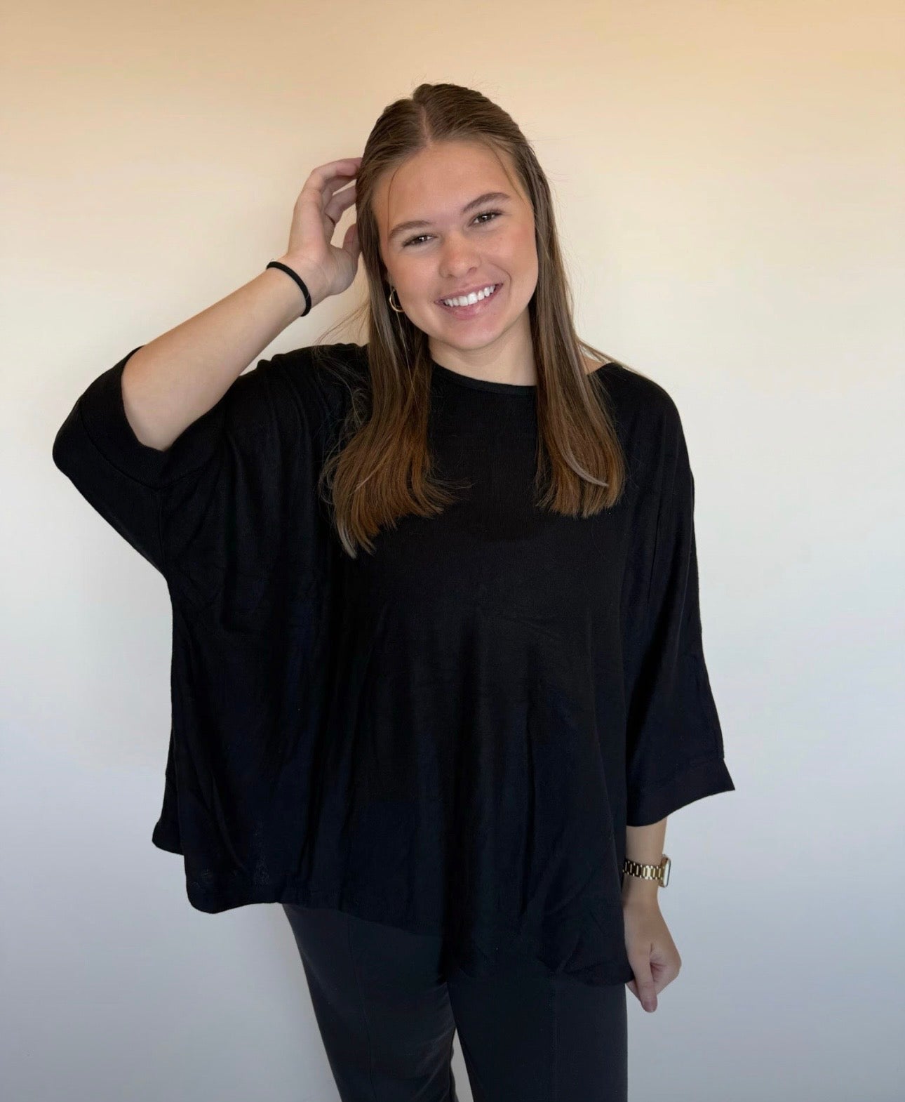 Woman wearing a black oversized sweater against a plain background