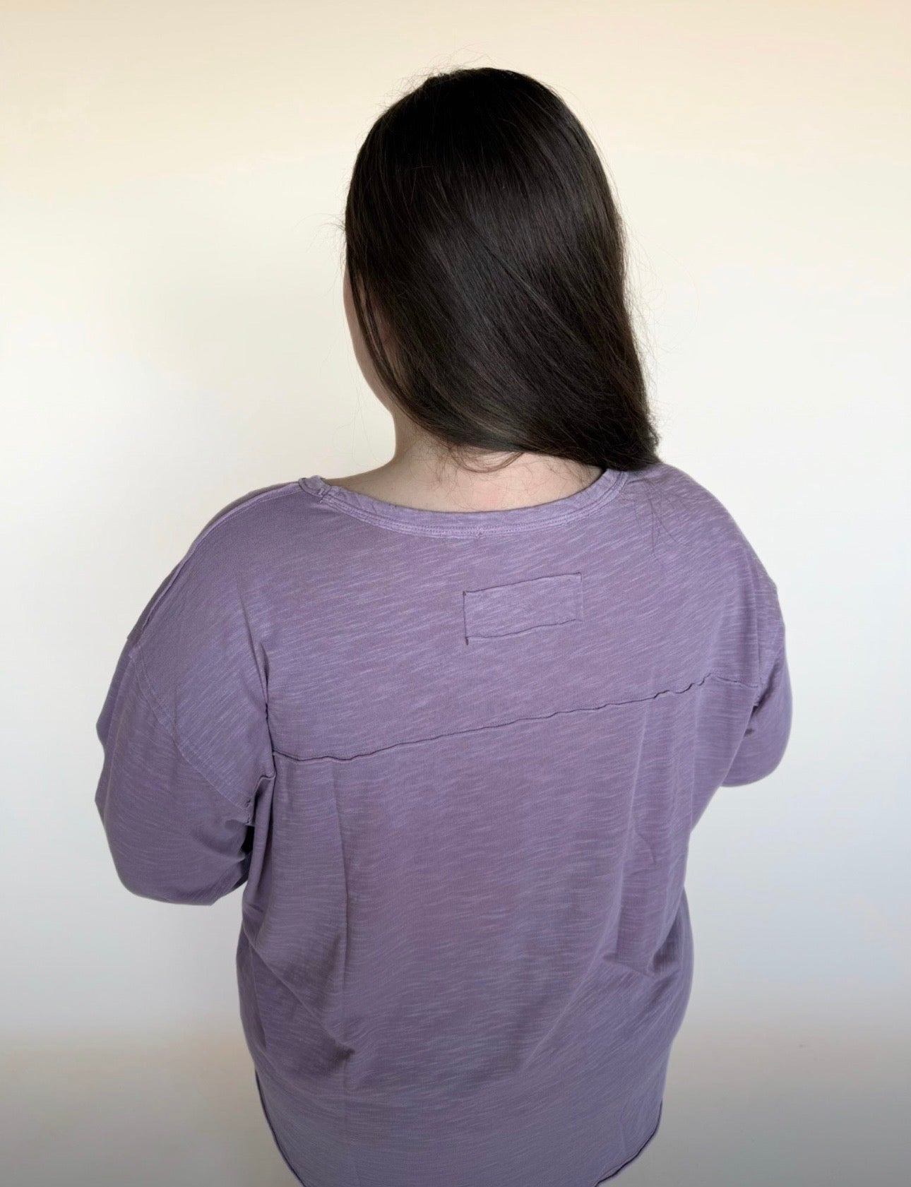 Person wearing a purple shirt with a plain background