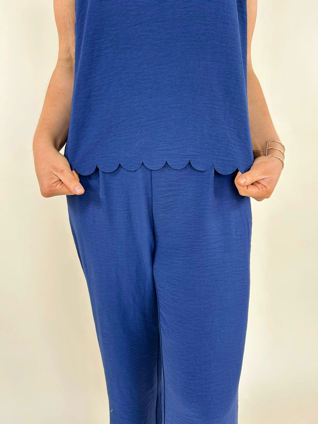 Close up front view of navy wide leg pants with scalloped hem top detail