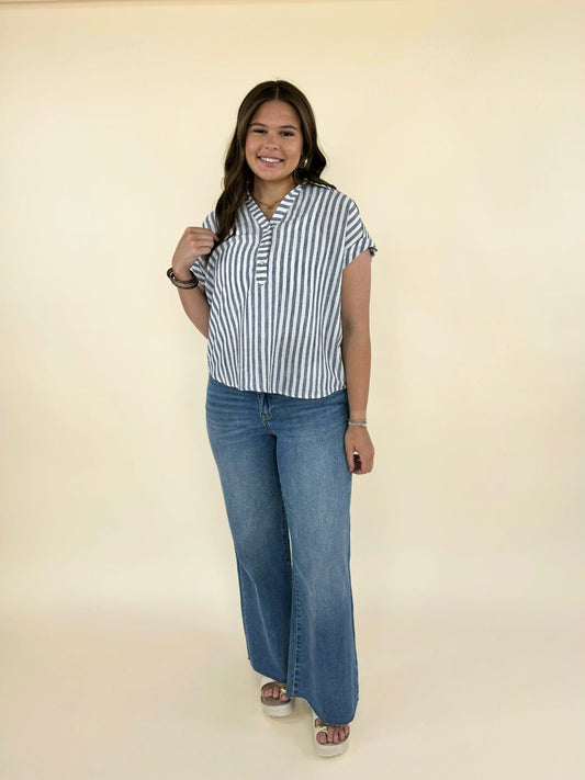 Full body front view of women’s blue and white striped blouse styled with wide leg denim jeans and platform sandals