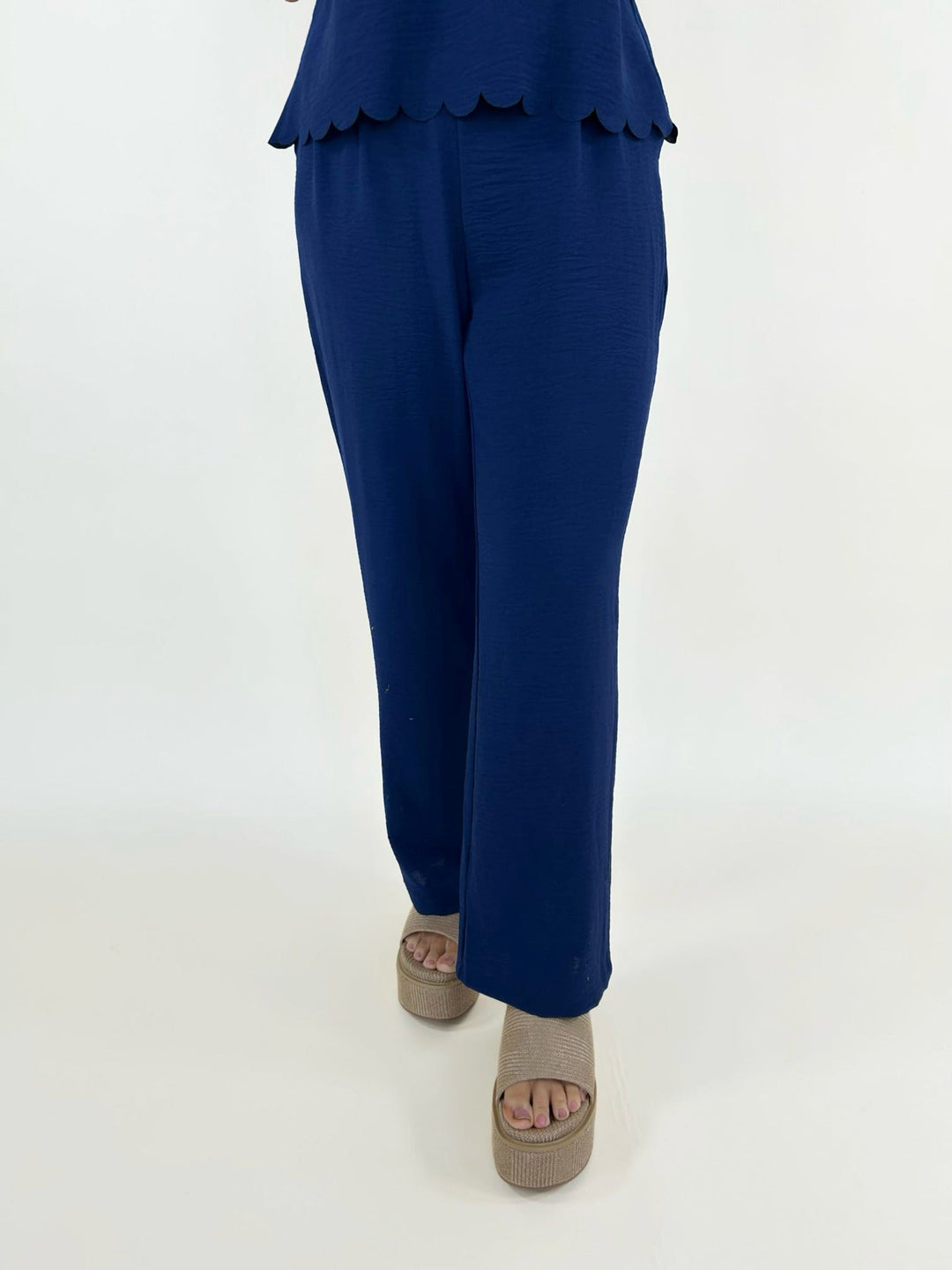 Front close view of navy wide leg pants styled with neutral platform sandals