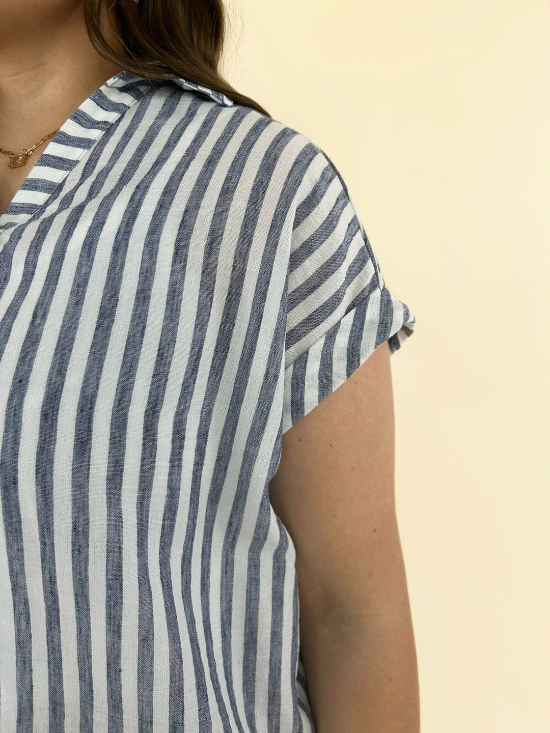 Close up detail of blue and white striped short sleeve blouse showing lightweight fabric and cap sleeve design