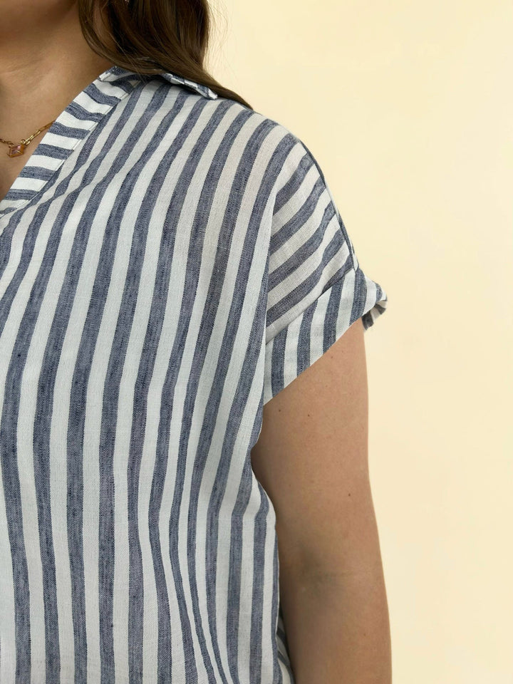 Close up detail of blue and white striped short sleeve blouse showing lightweight fabric and cap sleeve design