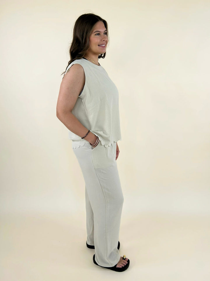 Side view of cream sleeveless top and wide leg pants set styled with black slide sandals
