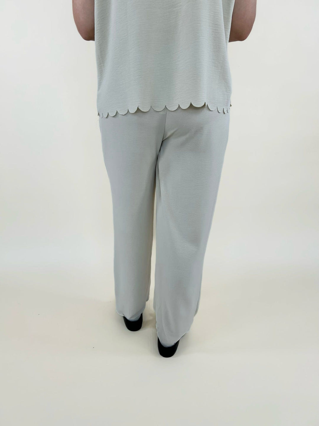 Back view of cream two piece outfit featuring scalloped hem top and flowy wide leg pants