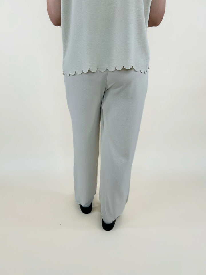 Back view of cream two piece outfit featuring scalloped hem top and flowy wide leg pants
