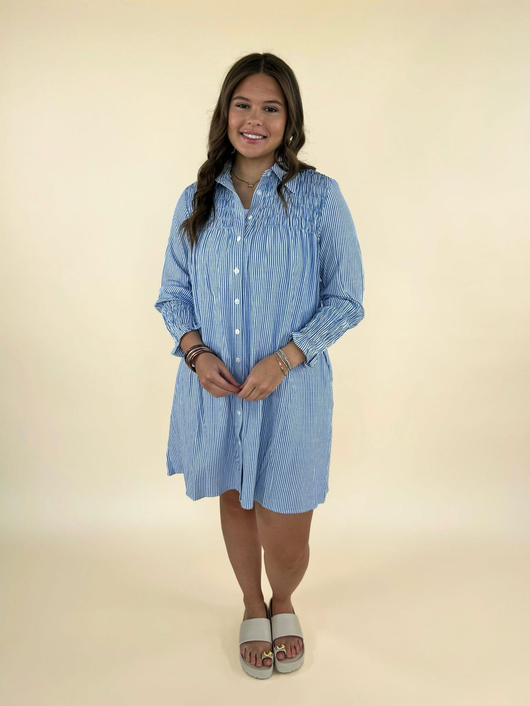 Front full body view of women’s blue and white striped button down shirt dress styled with slide sandals